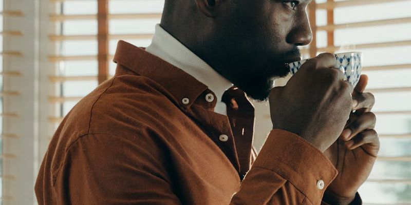 Person peacefully drinking tea and looking out a window.